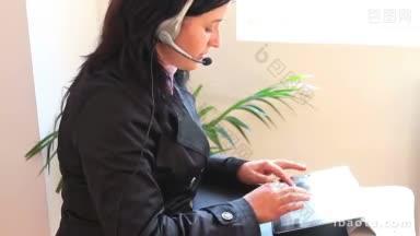 戴着耳机的女人<strong>一边</strong>打电话<strong>一边</strong>在平板电脑上打字